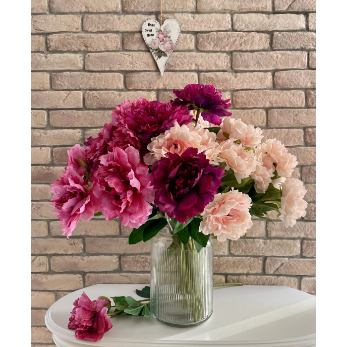 Open dark pink openwork peony with a bud on a branch